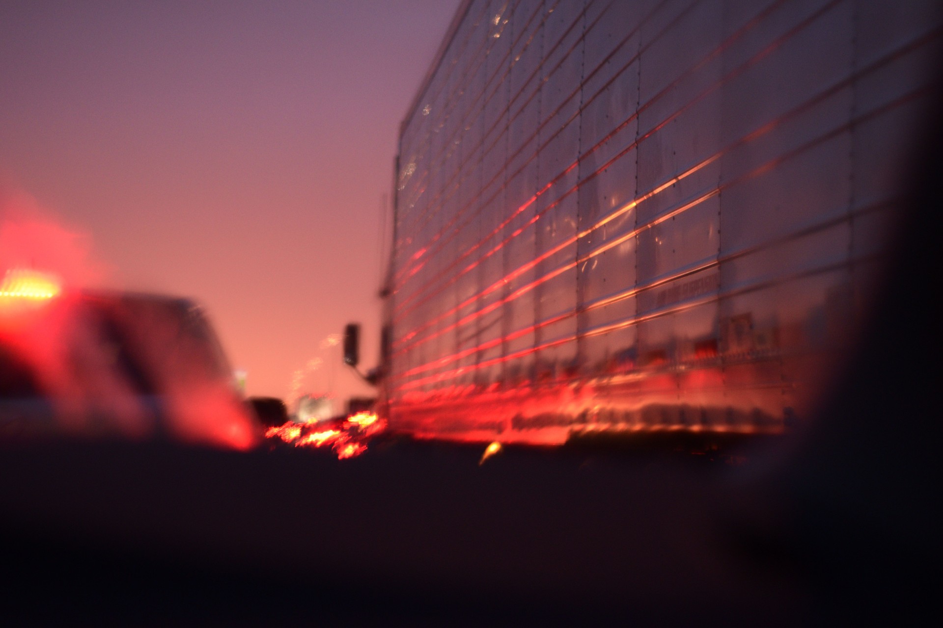 Looking Through A Rain Covered Windshield While Stuck In Stuck In Traffic During A Beautiful Sunset